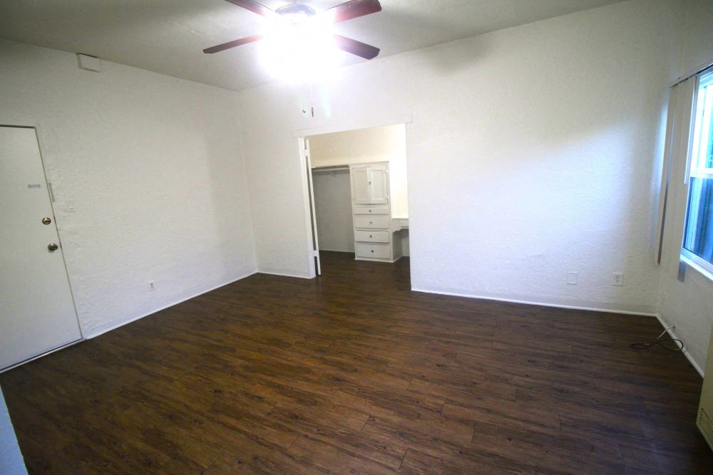 an empty living room with wood floors and a ceiling fan